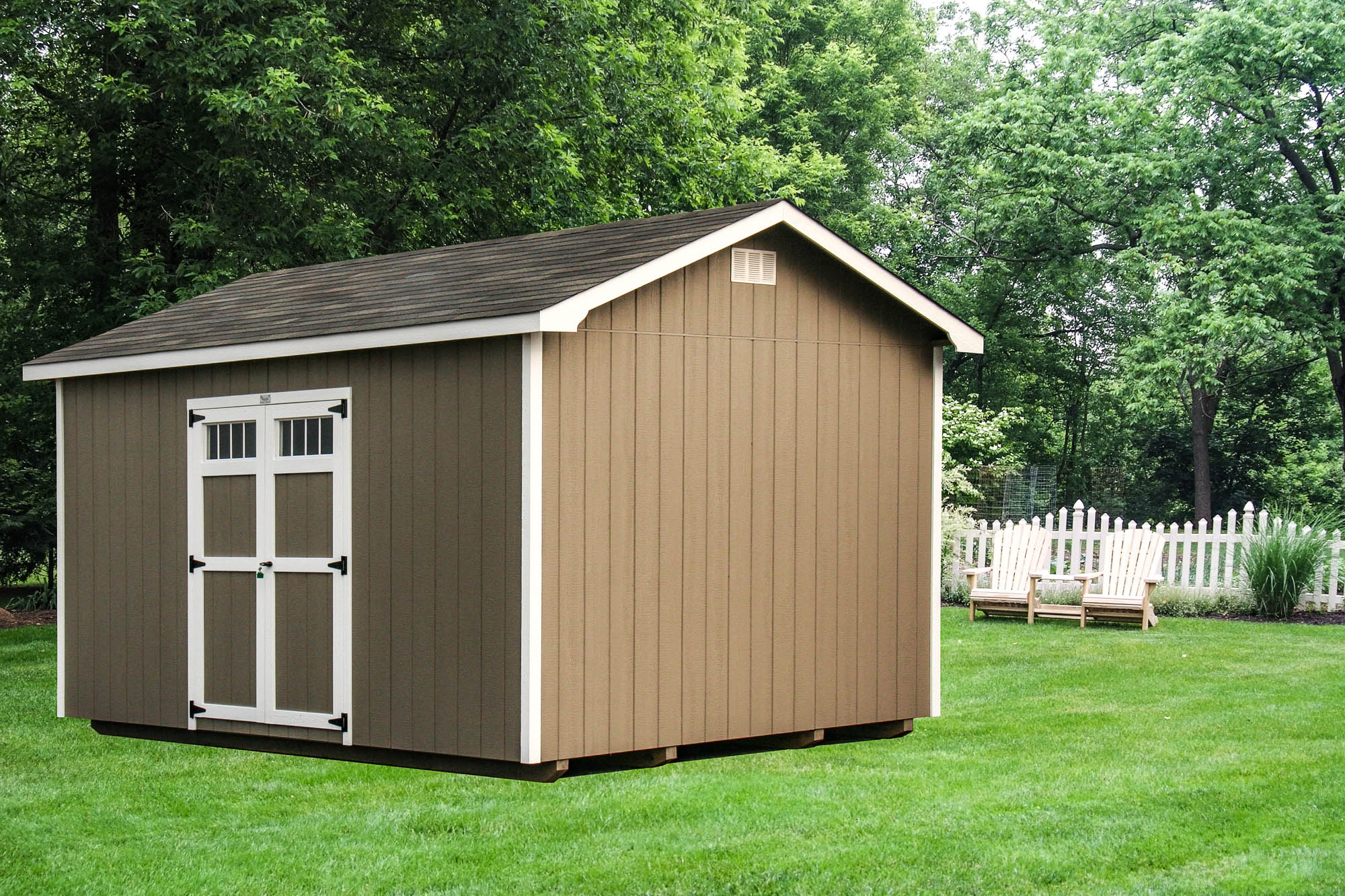 Brown shed with white trim and double doors, set on a grassy lawn surrounded by trees and outdoor seating.