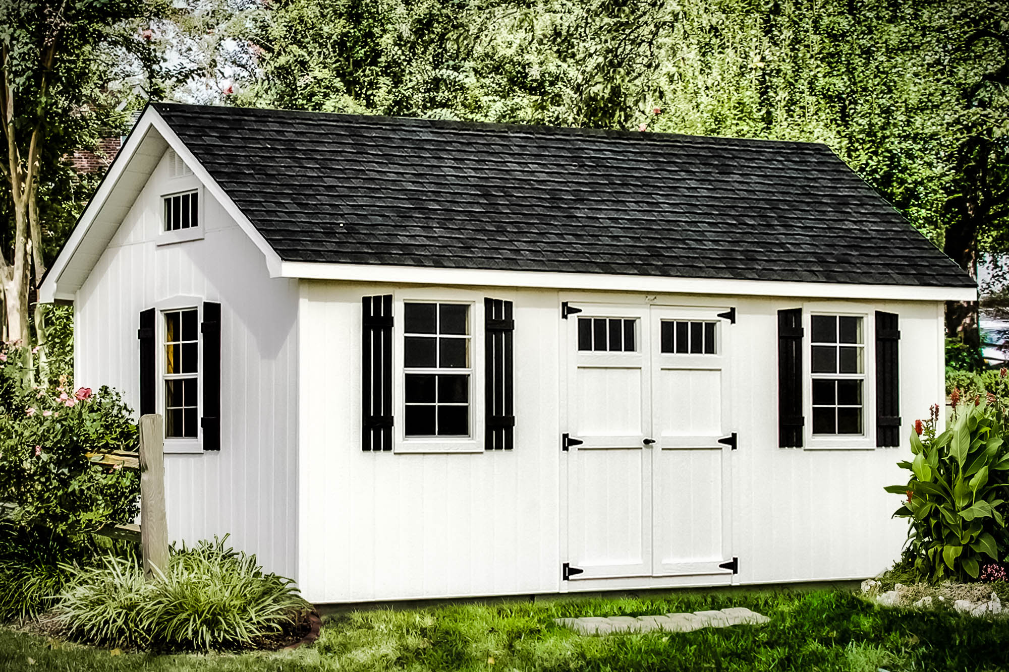 White shed with black shutters and roof, featuring double doors and windows, surrounded by trees and shrubs.