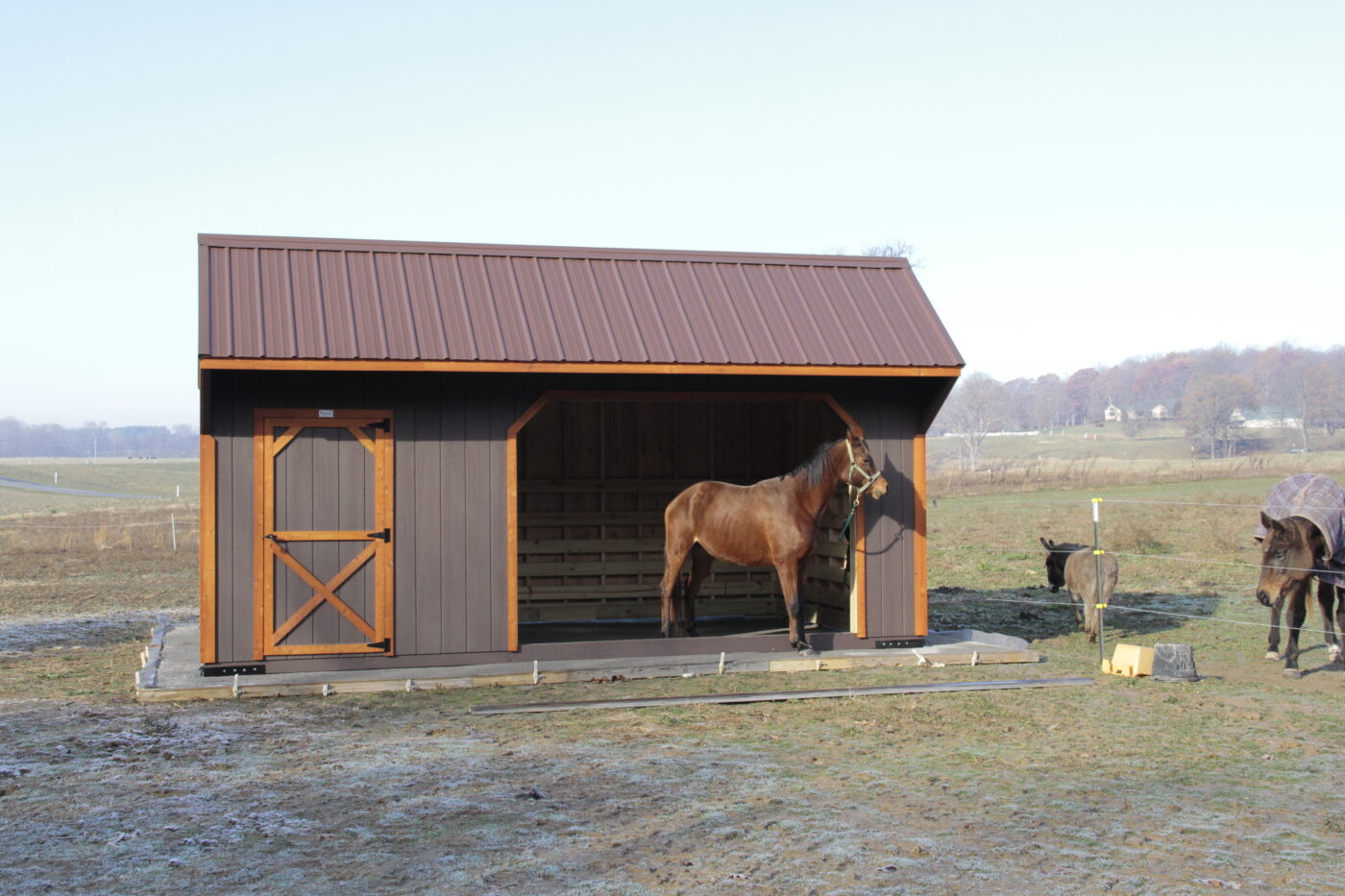 brown and orange trimmed horse barns in Nashville TN with red metal roof