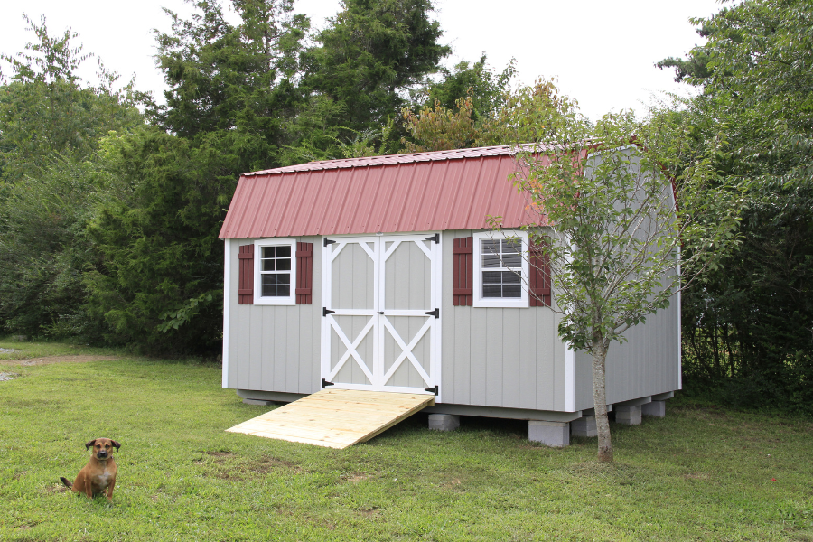 gray deluxe sheds in Nashville with red metal roof and shutters white trim and ramp leading up to double doors