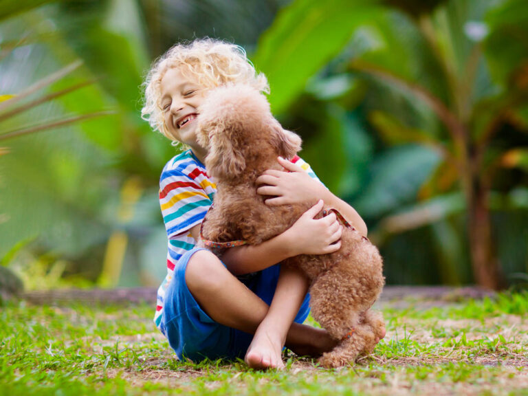 Blonde happy child hugging brown puppy to indicate Overholt's Family-owned status
